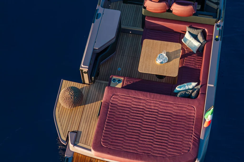 Area relax a poppa del Cranchi A32 Luxury Tender: divani, tavolo centrale e prendisole con finiture di pregio.