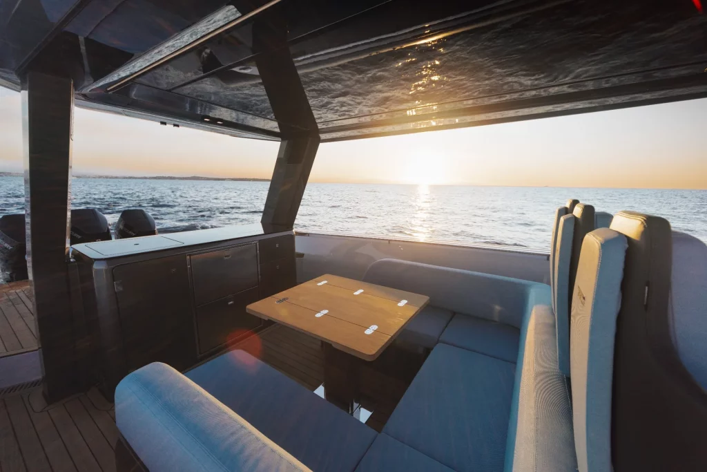 Pirelli 47 Speedboats: dinette di poppa con tavolo e divani sotto T-top, atmosfera al tramonto in rada.