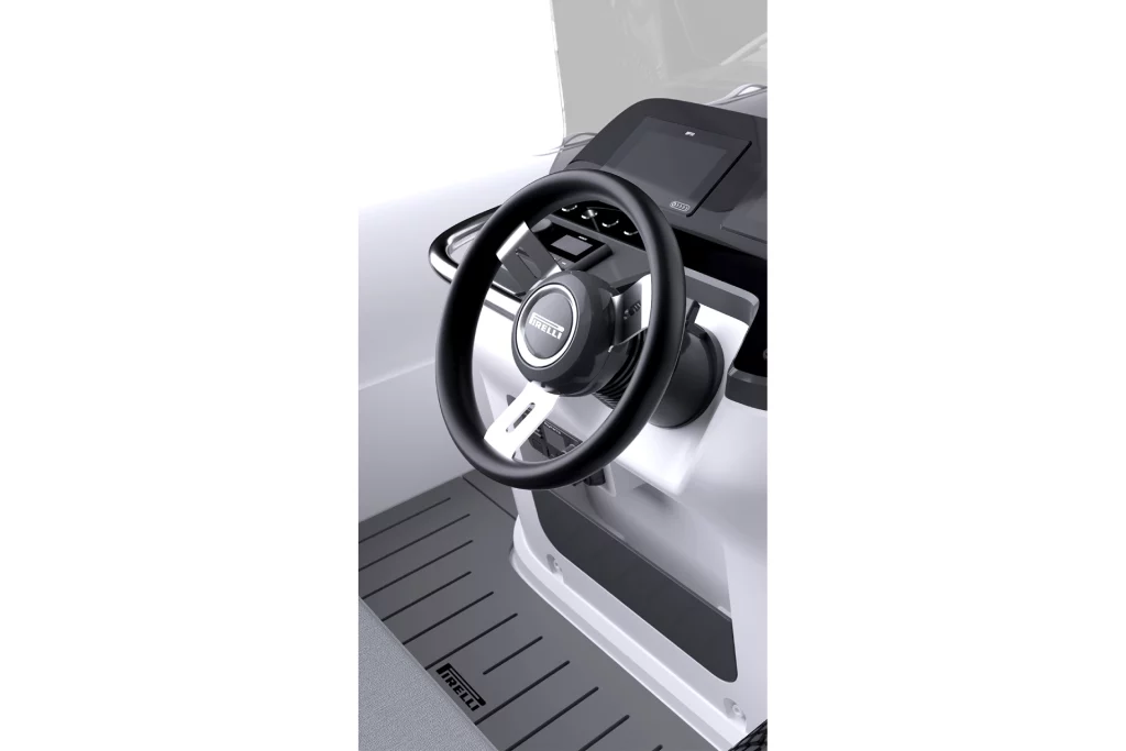 Dettaglio della console di guida del Pirelli X460 con volante brandizzato, display e comandi di plancia su finiture grigio/nero.