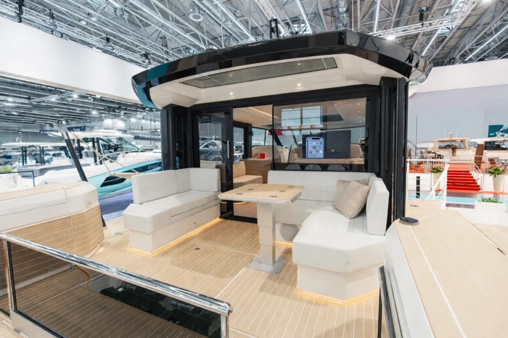 Cockpit di poppa del Saxdor 460 GTC con divani a U, tavolo centrale e hard top, allestimento in fiera nautica.