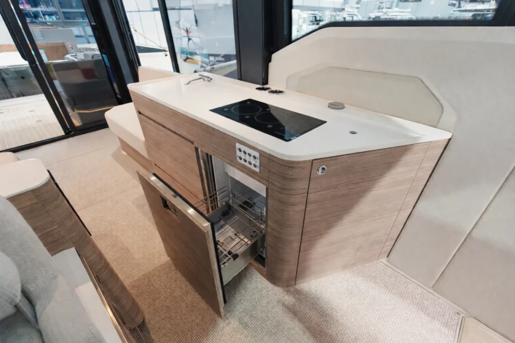 Cucina (galley) del Saxdor 460 GTC con piano a induzione, lavello e cassetti estraibili, finiture moderne effetto legno.