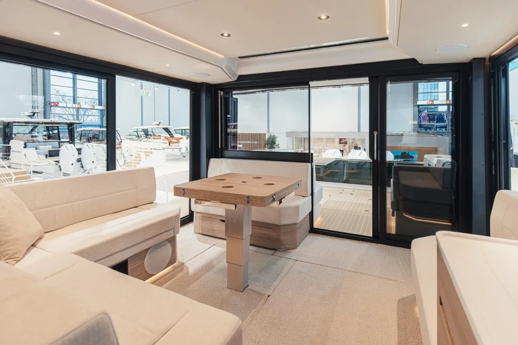 Salone del Saxdor 460 GTC con dinette e tavolo, ampie vetrate panoramiche e porta scorrevole verso il pozzetto.